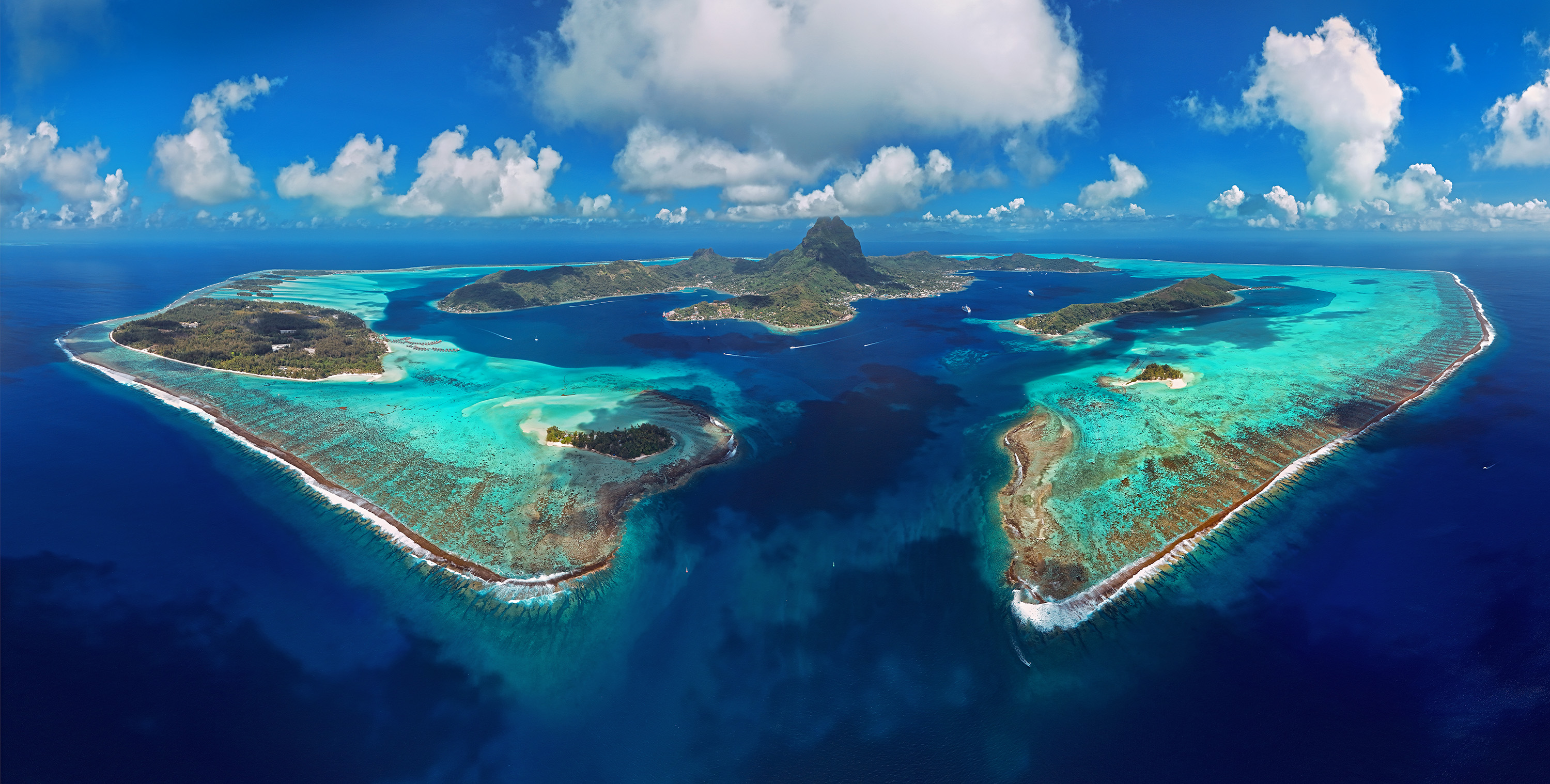 Vue aérienne de Bora Bora avec son lagon turquoise, sa barrière de corail et le mont Otemanu en arrière-plan, prise lors d'une croisière avec l'Aranui